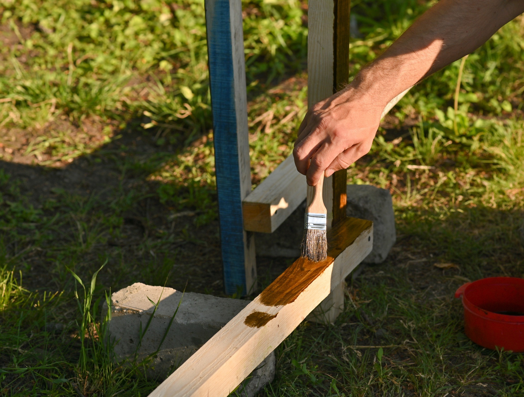 A man paints wood with a brush